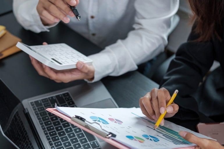 Two people review spreadsheets
