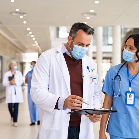 General practitioner and young nurse wearing surgical face masks.