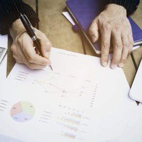 Selective focus man hand with pen check calculating the monthly of debt bills bank as a papers graph documents expenses and payment in the office