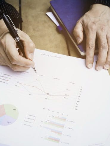 Selective focus man hand with pen check calculating the monthly of debt bills bank as a papers graph documents expenses and payment in the office