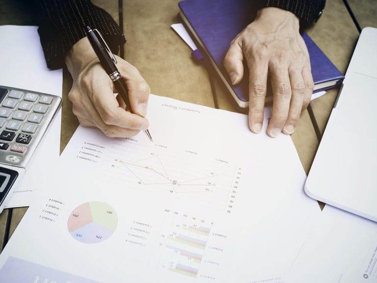 Selective focus man hand with pen check calculating the monthly of debt bills bank as a papers graph documents expenses and payment in the office