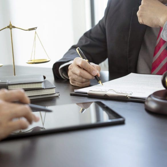 The lawyer is reviewing the draft of legal documents or contracts for clients near the staff or the client is checking work together by using a tablet.