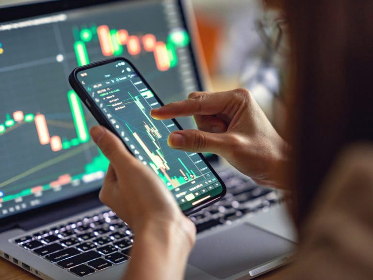 Closeup - Woman is checking Bitcoin price chart on digital exchange on smartphone, cryptocurrency future price action prediction.