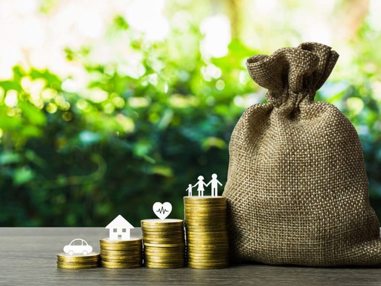 Savings money for the future concepts. Family member, car, house, healthy on stack of coins with money bag on wood table. Depicts saving for wealth and life. fundraising concept.