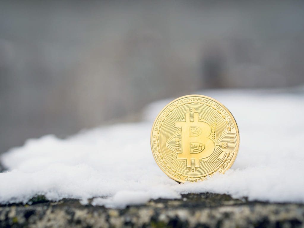 A gold Bitcoin placed in snow on concrete. Isolated scene of cryptocurrency in snow