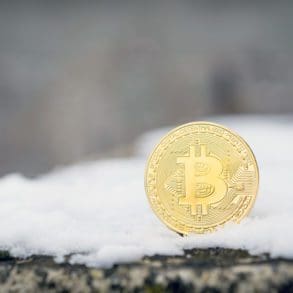 A gold Bitcoin placed in snow on concrete. Isolated scene of cryptocurrency in snow