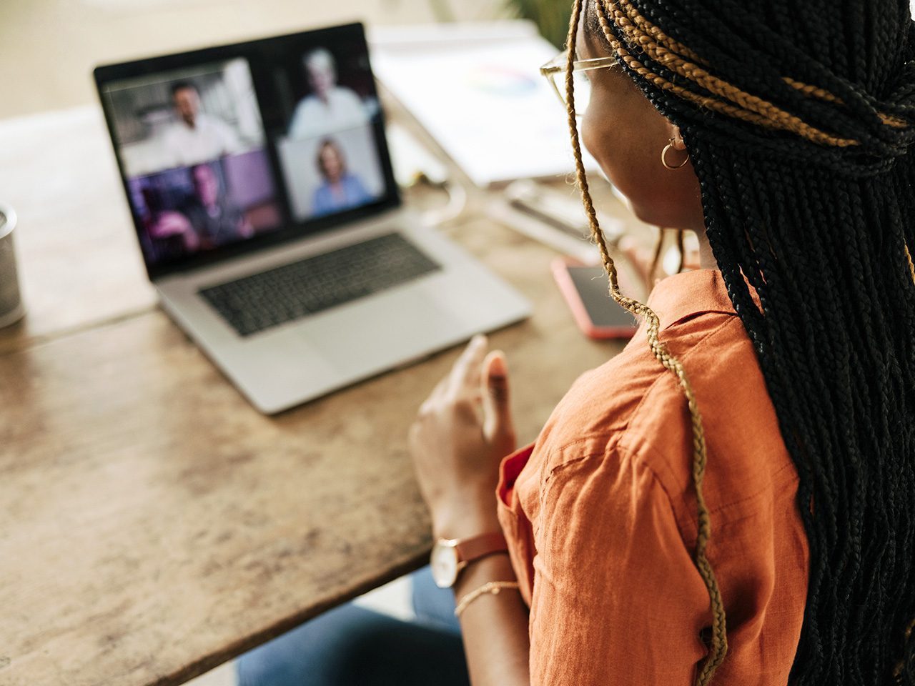 Graphic designer attending a virtual meeting with her clients. Creative female freelancer using a laptop for a video call.  Young woman working on a new project in her home office.