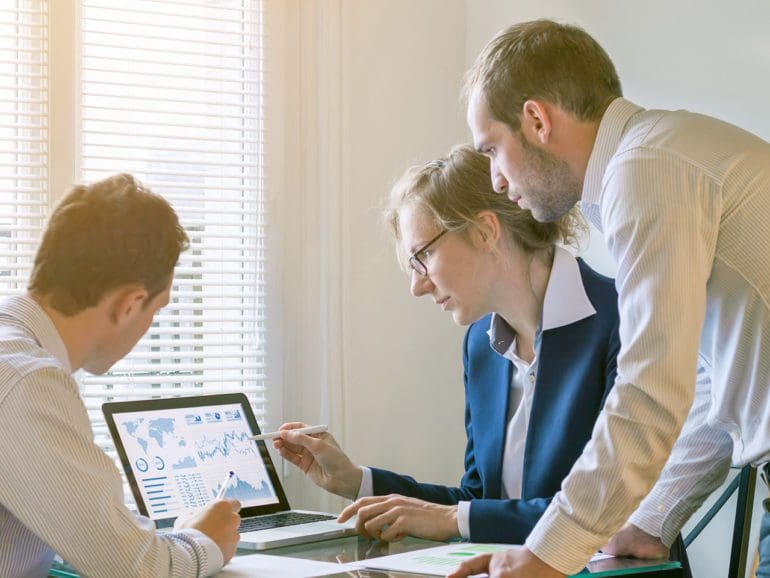 Team of finance people discussing charts and key performance indicator (KPI) on computer screen with business intelligence (BI) in meeting room, corporate revenue, fintech