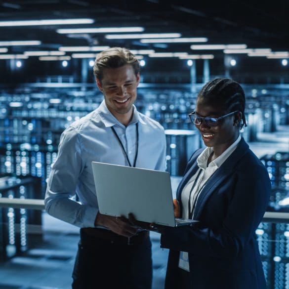 Data Center Female System Administrator and Male IT Specialist talk, Use Laptop. Information Technology Engineers work on Cyber Security Protection in Cloud Computing Server Farm.