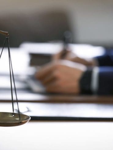 Scales of justice and blurred lawyer on background. Banner design