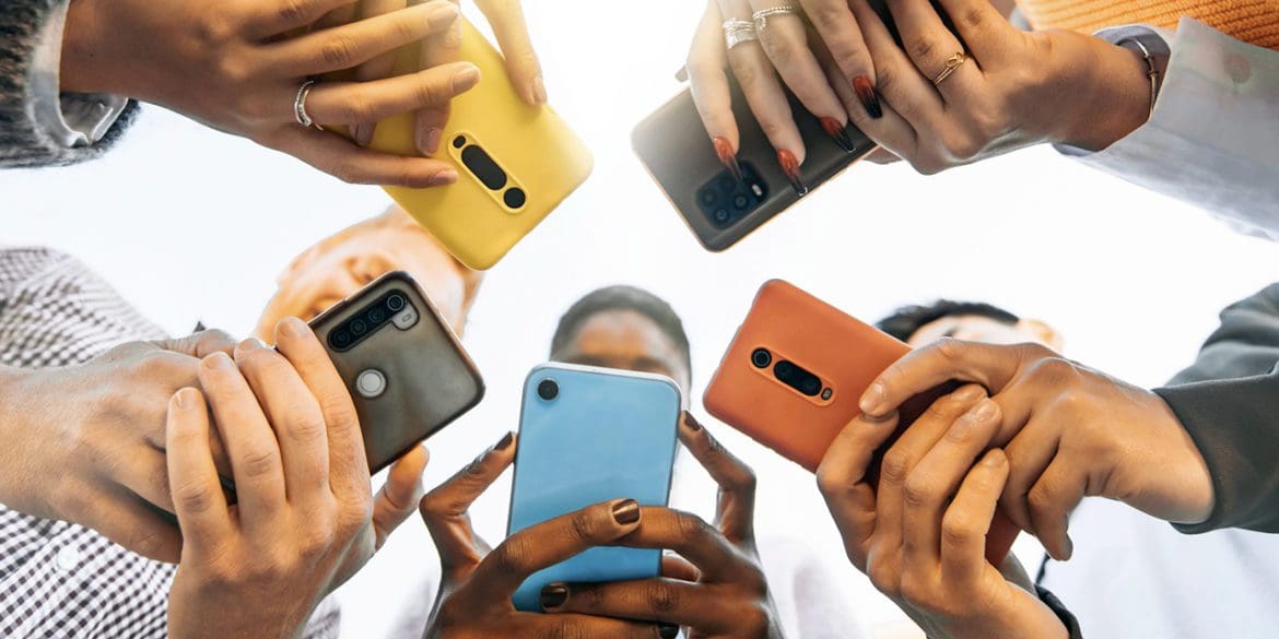 Teens in circle holding smart mobile phones - Multicultural young people using cellphones outside - Teenagers addicted to new technology concept