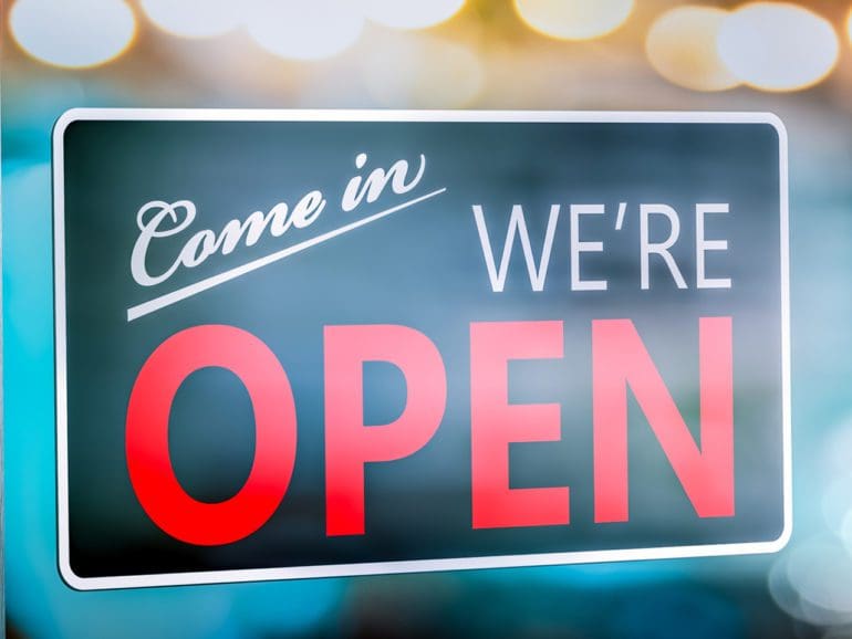 Small Business Store Front With "Come In We're Open" Sign Hanging On Window - Small Business Concept