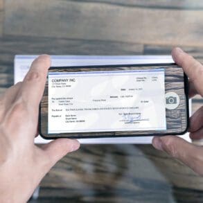 Man Taking Photo Of Cheque To Make Remote Deposit In bank