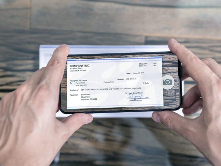 Man Taking Photo Of Cheque To Make Remote Deposit In bank