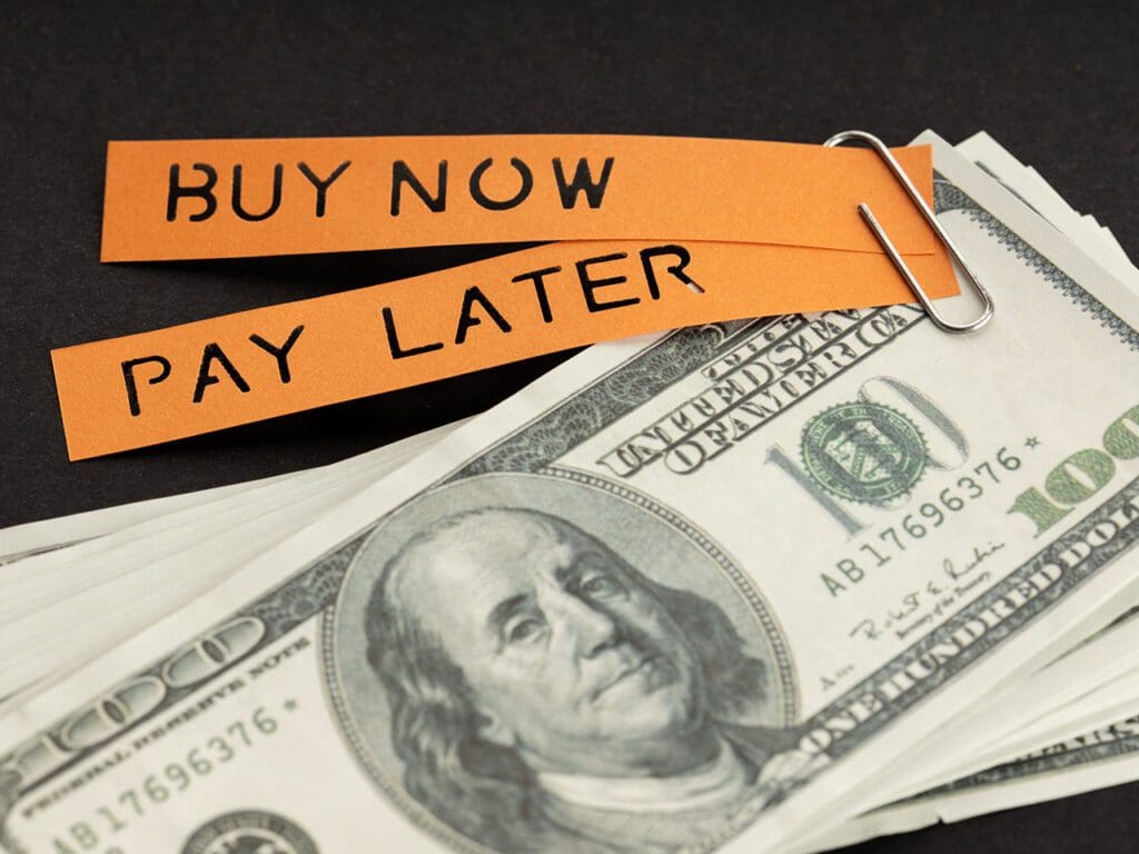 BNPL or Buy Now Pay Later concept. Dollar bills and label with message on black background