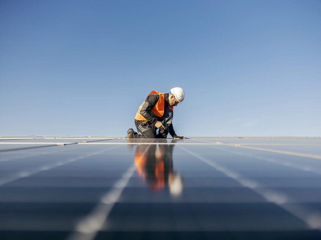 A handyman on the rooftop installing solar panels.